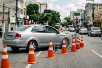 Alterações no trânsito: cones laranjas de trânsito posicionados no asfalto sinalizando interdição em avenida urbana durante o dia.