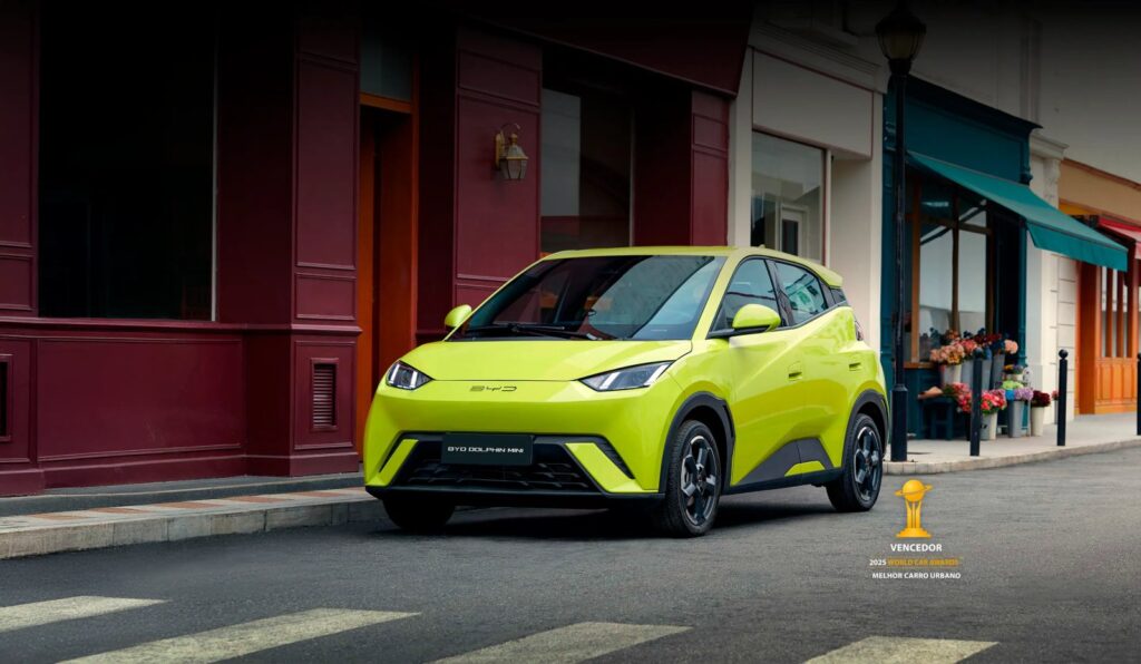 BYD Dolphin Mini tem menor consumo energético no Ranking Mauá com 342 km urbanos 3 BYD Dolphin Mini: carro compacto elétrico conectado a cabo de carregamento em rua arborizada com prédios urbanos ao fundo. — foto 2