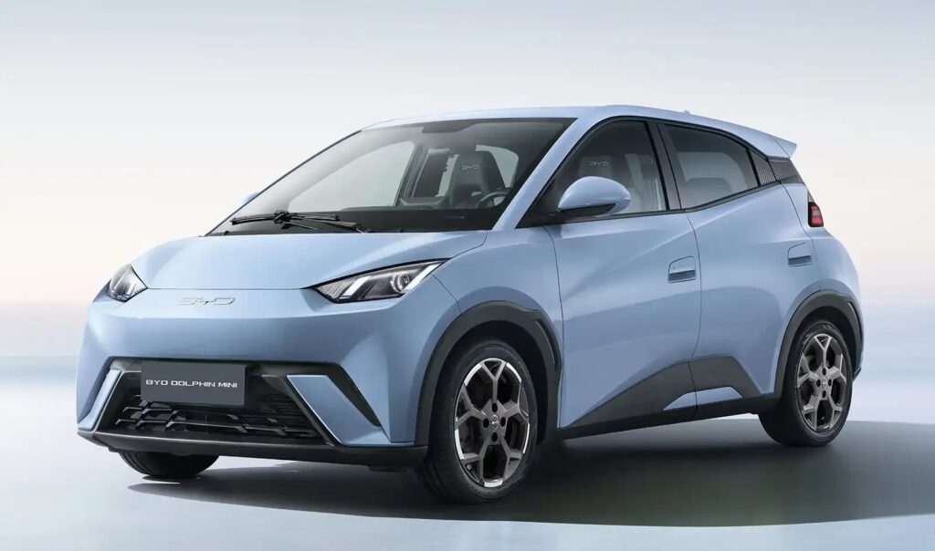 BYD Dolphin Mini tem menor consumo energético no Ranking Mauá com 342 km urbanos 4 BYD Dolphin Mini: carro compacto elétrico conectado a cabo de carregamento em rua arborizada com prédios urbanos ao fundo. — foto 3