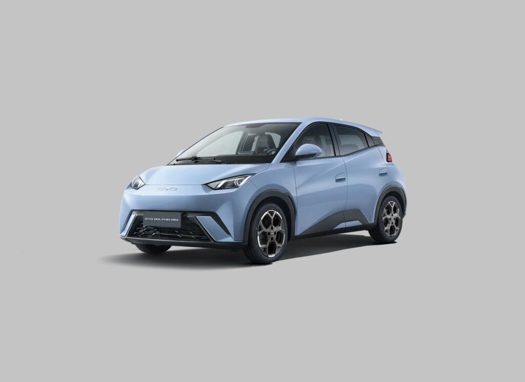 BYD Dolphin Mini tem menor consumo energético no Ranking Mauá com 342 km urbanos 6 BYD Dolphin Mini: carro compacto elétrico conectado a cabo de carregamento em rua arborizada com prédios urbanos ao fundo. — foto 5