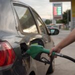 Motorista abastece carro flex com etanol num posto, cena da calculadora gasolina x etanol