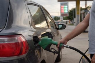 Motorista abastece carro flex com etanol num posto, cena da calculadora gasolina x etanol