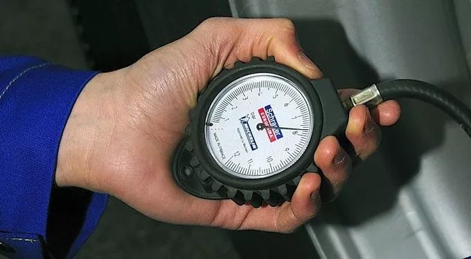 Calibrar pneus com nitrogênio: motorista verificando a calibragem da pressão dos pneus em bico de calibrador