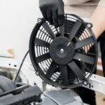 Ventoinha elétrica sendo instalada no cofre do motor, peça-chave da pressão no arrefecimento