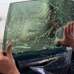 Insulfilm sendo aplicado no vidro lateral do carro por um profissional