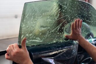 Insulfilm sendo aplicado no vidro lateral do carro por um profissional