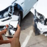 Celular fotografando os danos de um carro batido, tema da perda total no seguro