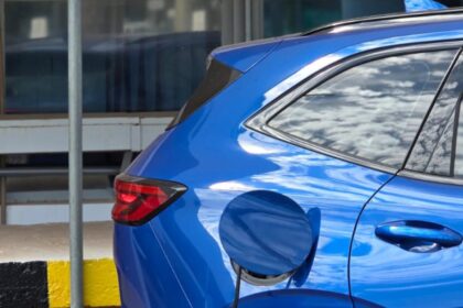 Carro el&eacute;trico novo ou usado a combust&atilde;o: conector de esta&ccedil;&atilde;o de recarga plugado em ve&iacute;culo el&eacute;trico urbano moderno.