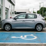 Carros PCD: vaga reservada com o símbolo de acessibilidade em frente a uma concessionária, com hatch 0 km estacionado