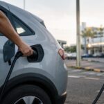 Motorista conecta o cabo de um eletroposto na tomada de recarga de um carro elétrico