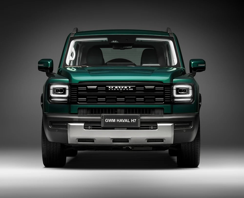 GWM Haval H7: sUV híbrido moderno em destaque no showroom envidraçado de uma concessionária com cliente e vendedor ao fundo de costas. — foto 2