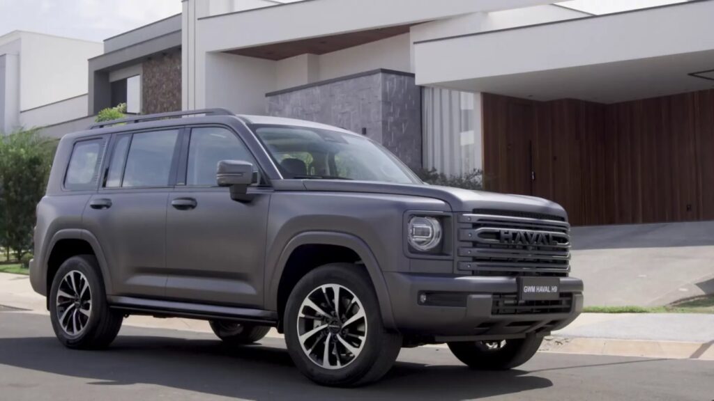 GWM Haval H7: sUV híbrido moderno em destaque no showroom envidraçado de uma concessionária com cliente e vendedor ao fundo de costas. — foto 5