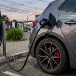 ID. Polo GTI: plugue de carregador elétrico conectado a hatch esportivo moderno com pinça de freio esportiva em eletroposto rodoviário.