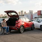 Pcd nissan: nissan PCD: pessoa em cadeira de rodas ao lado de um Nissan Kicks 0 km com o porta-malas aberto
