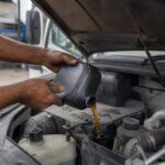 Mecânico colocando óleo 15W40 diesel no motor de um caminhão na oficina