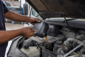 Mecânico colocando óleo 15W40 diesel no motor de um caminhão na oficina