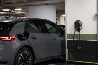 Ponto de recarga de carro elétrico em condomínio: carregador de parede ligado a um carro elétrico na vaga de garagem de um condomínio