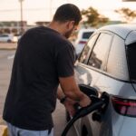 Posto de recarga de carro elétrico quanto custa: motorista conecta o cabo do carregador rápido de um posto de recarga ao carro elétrico