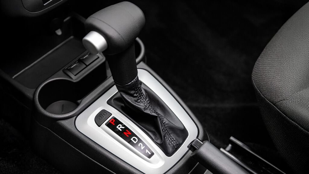Câmbio automático dando tranco ao engatar D ou R: o que pode ser? 2 Tranco no câmbio automático: mecânico inspecionando alavanca e componentes de transmissão automática em oficina mecânica