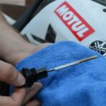 Troca de óleo moto: mecânico drenando o óleo do motor numa oficina