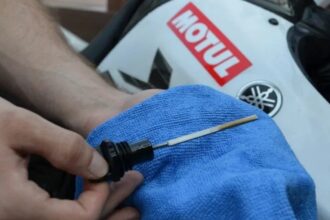 Troca de óleo moto: mecânico drenando o óleo do motor numa oficina