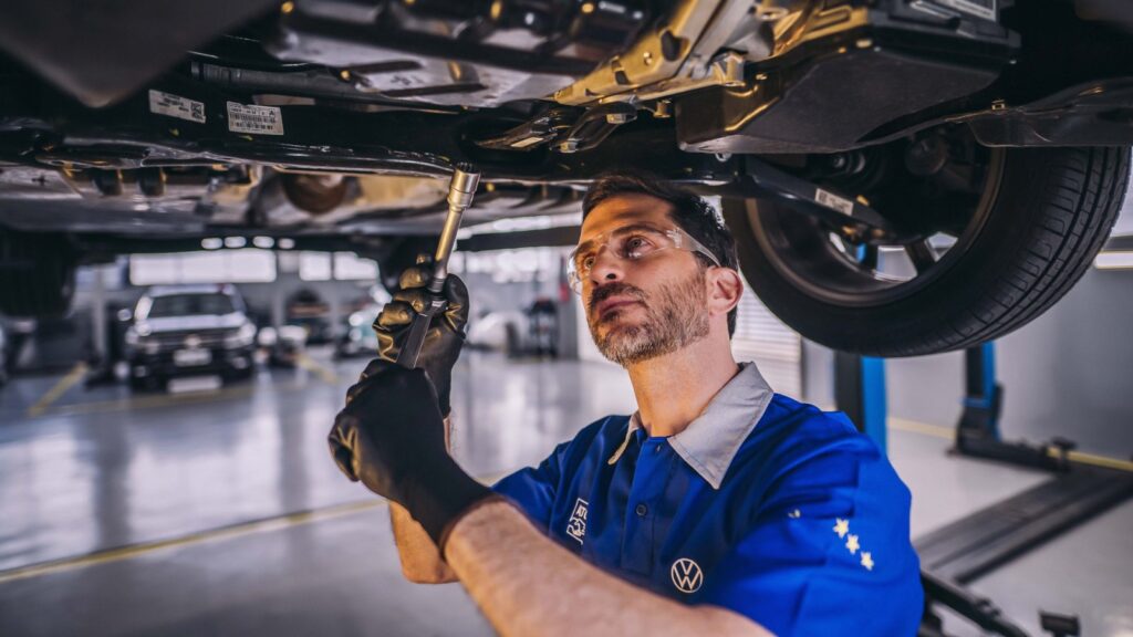 Mecânico realizando a troca do filtro de óleo no motor de um veículo em uma oficina mecânica.
